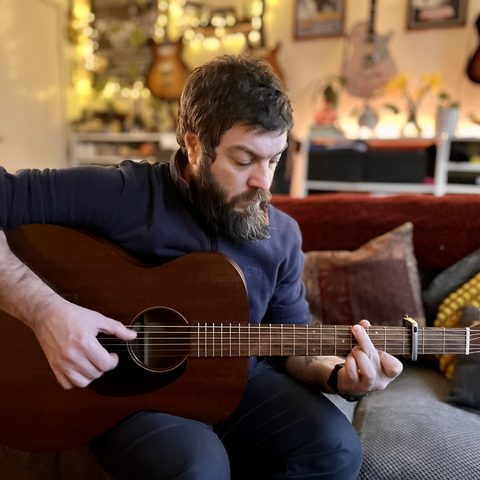 Matthew playing acoustic guitar at home