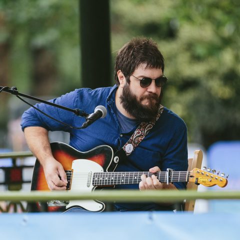 Matthew playing guitar at an outdoor show